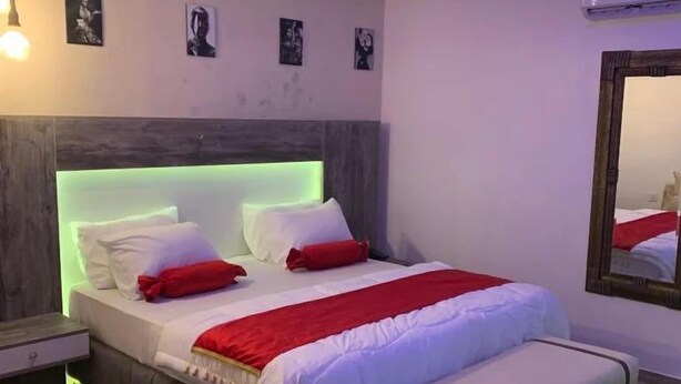 A modern bedroom with a bed, bedside tables, a mirror, and wall art. - TAI HOTEL LEKKI (Lekki)