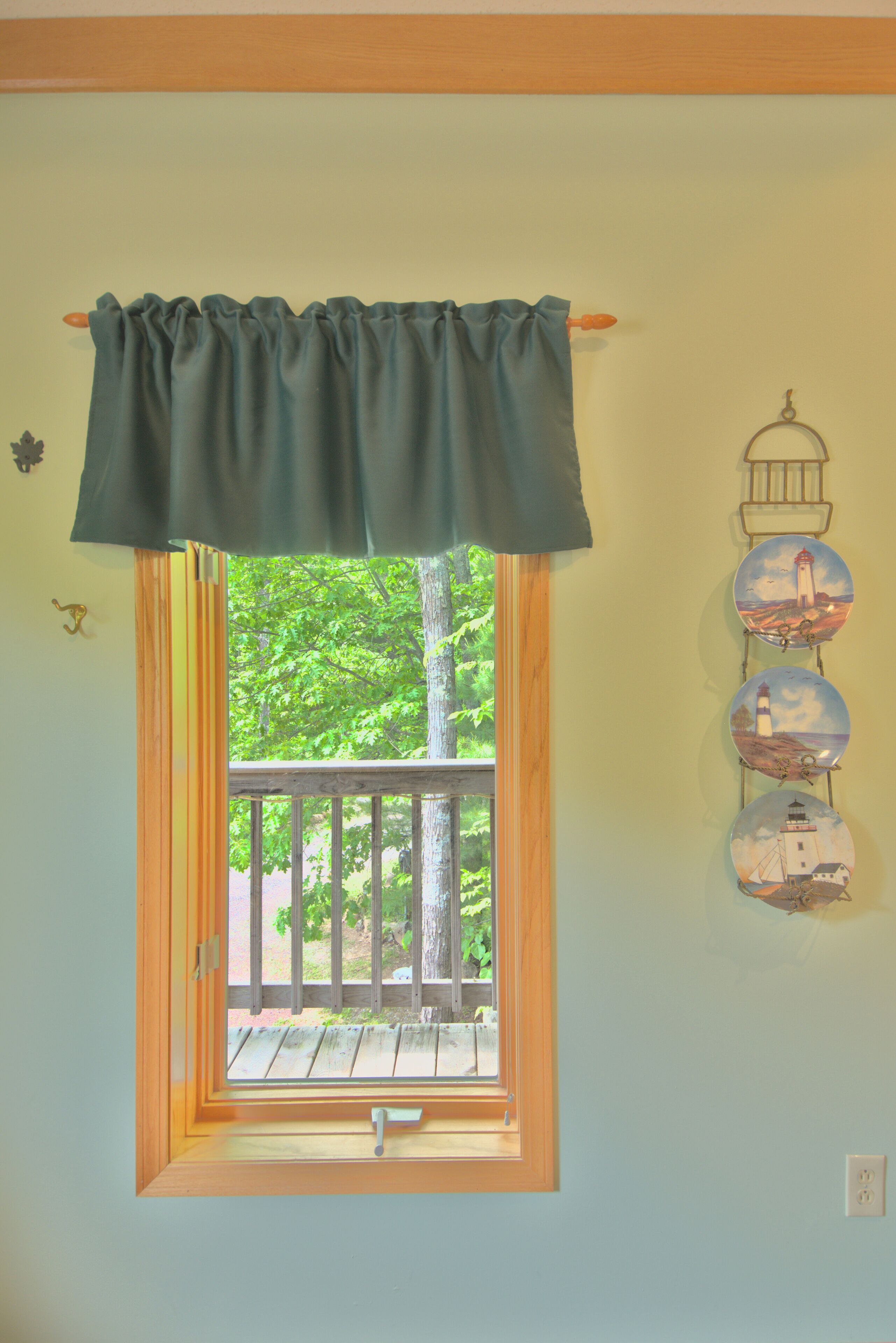 A room with a window featuring a wooden frame and a view of trees.