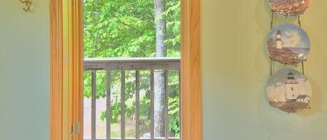 A room with a window featuring a wooden frame and a view of trees.
