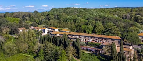 A hillside hotel with terracotta-roofed buildings, surrounded by lush greenery and a clear blue sky.