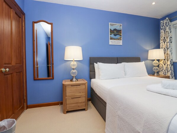 Habitación de hotel con una cama grande, dos mesitas de noche con lámparas, un armario de madera y un cuadro enmarcado en la pared.