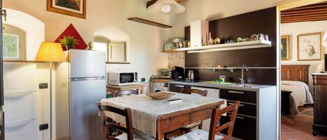 A compact kitchen with a dining table, chairs, a refrigerator, microwave, and a sink.