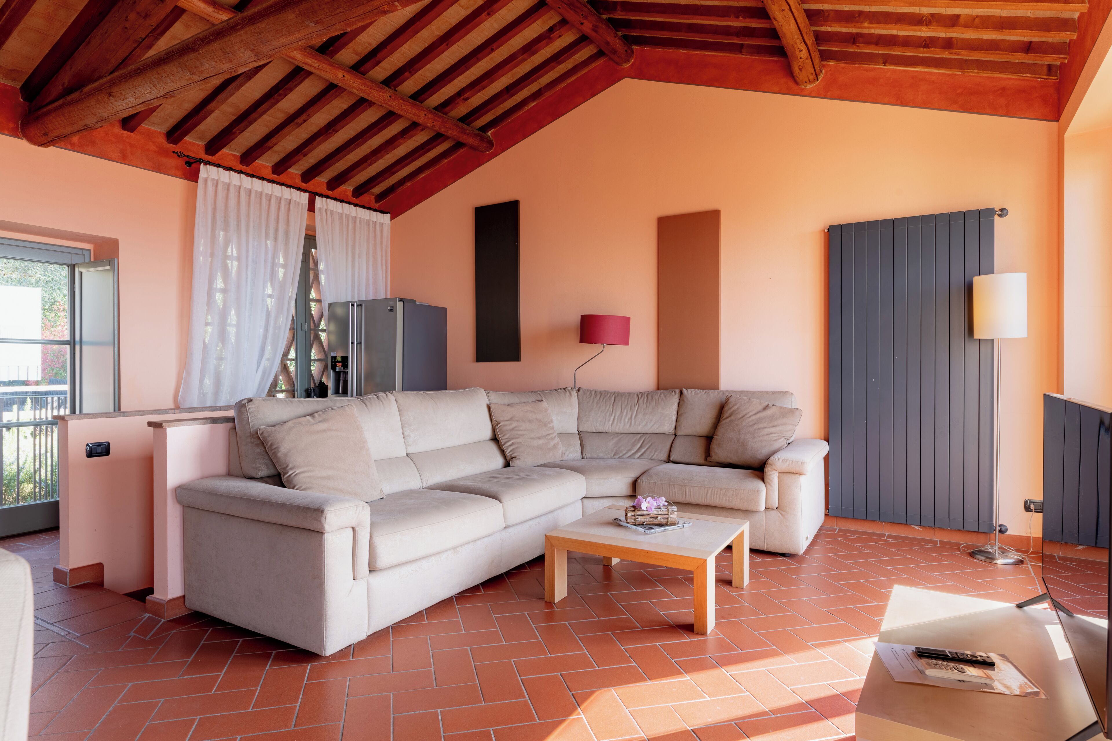 Un salón con sofá modular, una mesa de centro, una lámpara y un radiador.