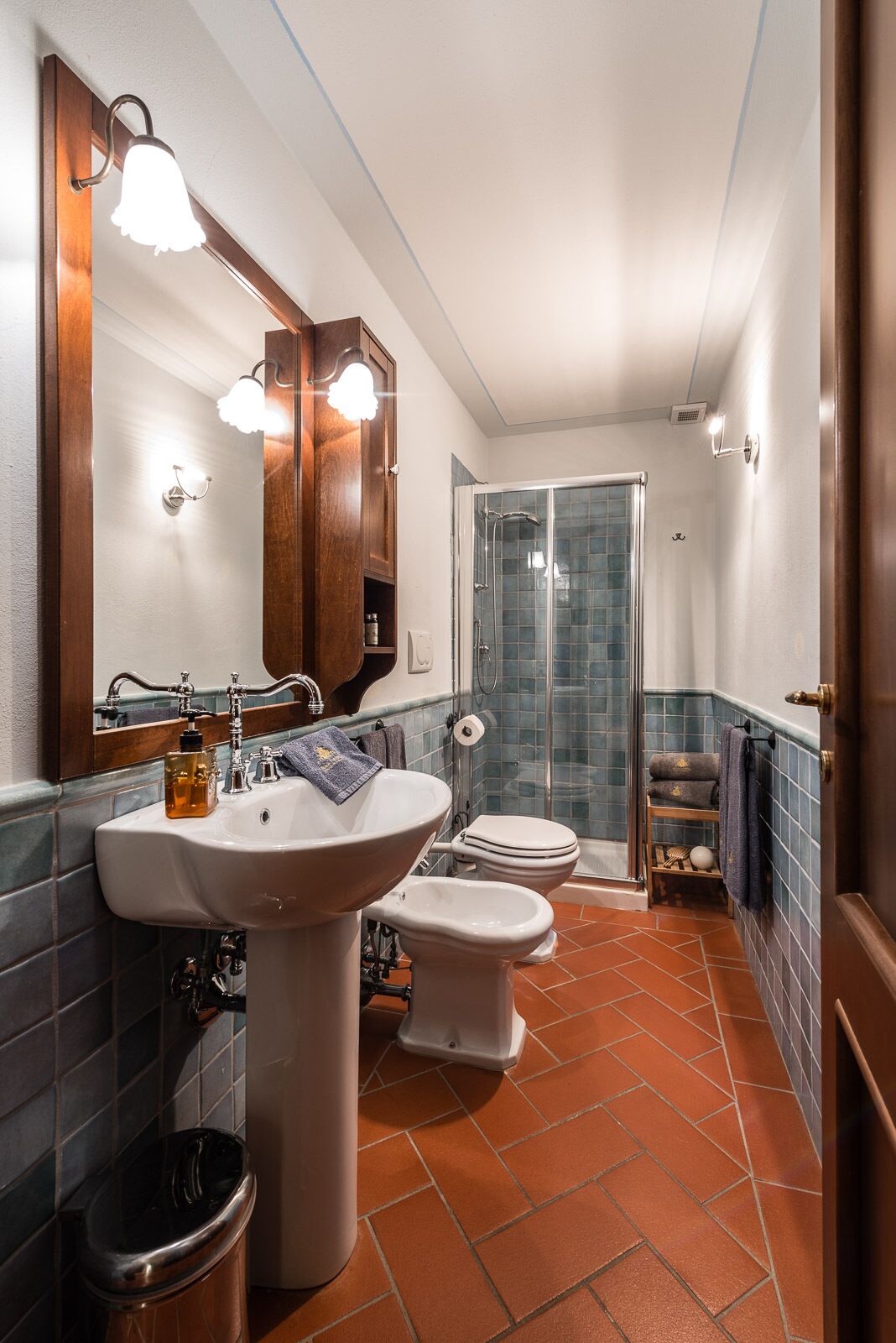 Baño con lavamanos, dos inodoros, ducha y espejo.