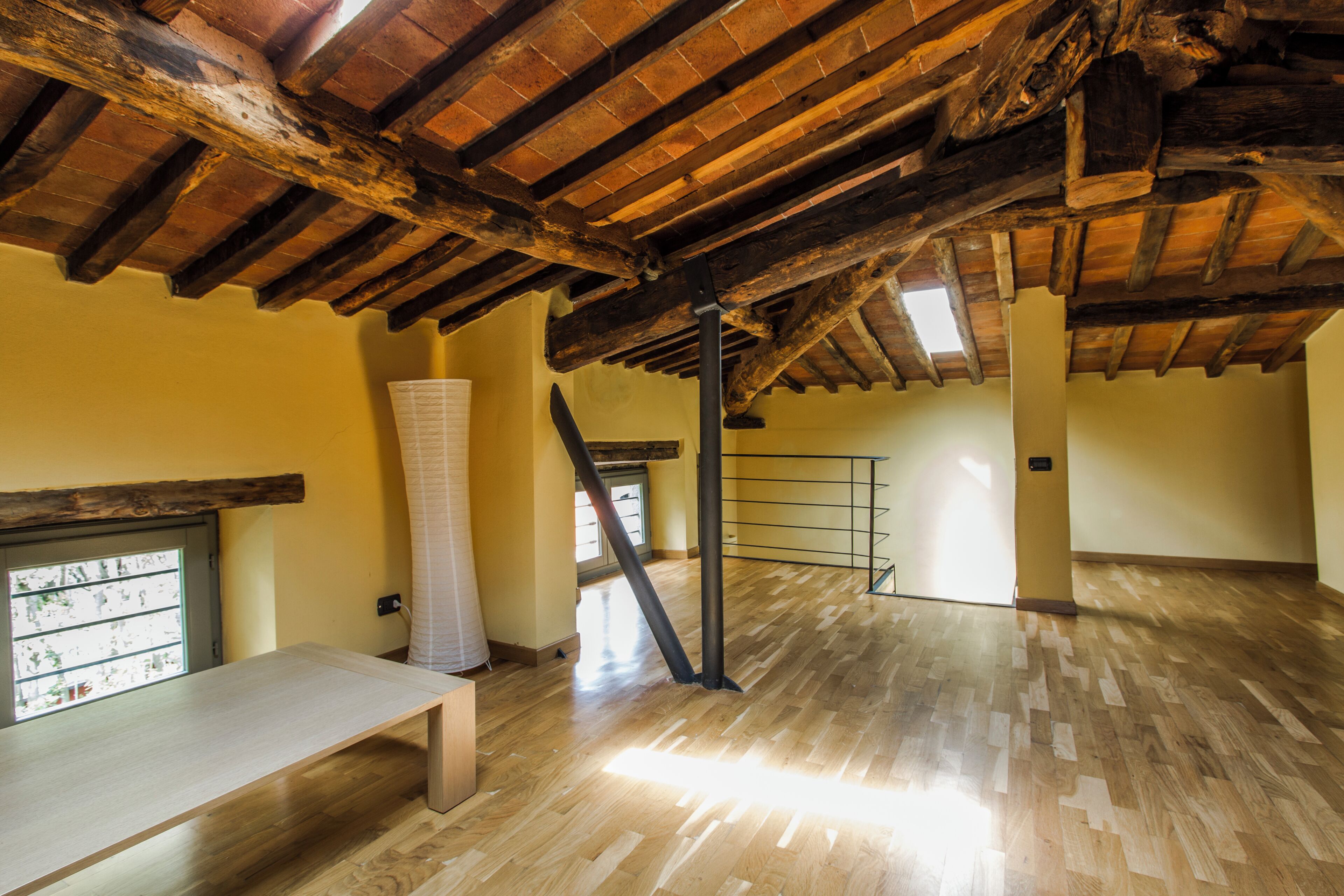 An interior with a wooden ceiling, a bench, and a window with blinds.