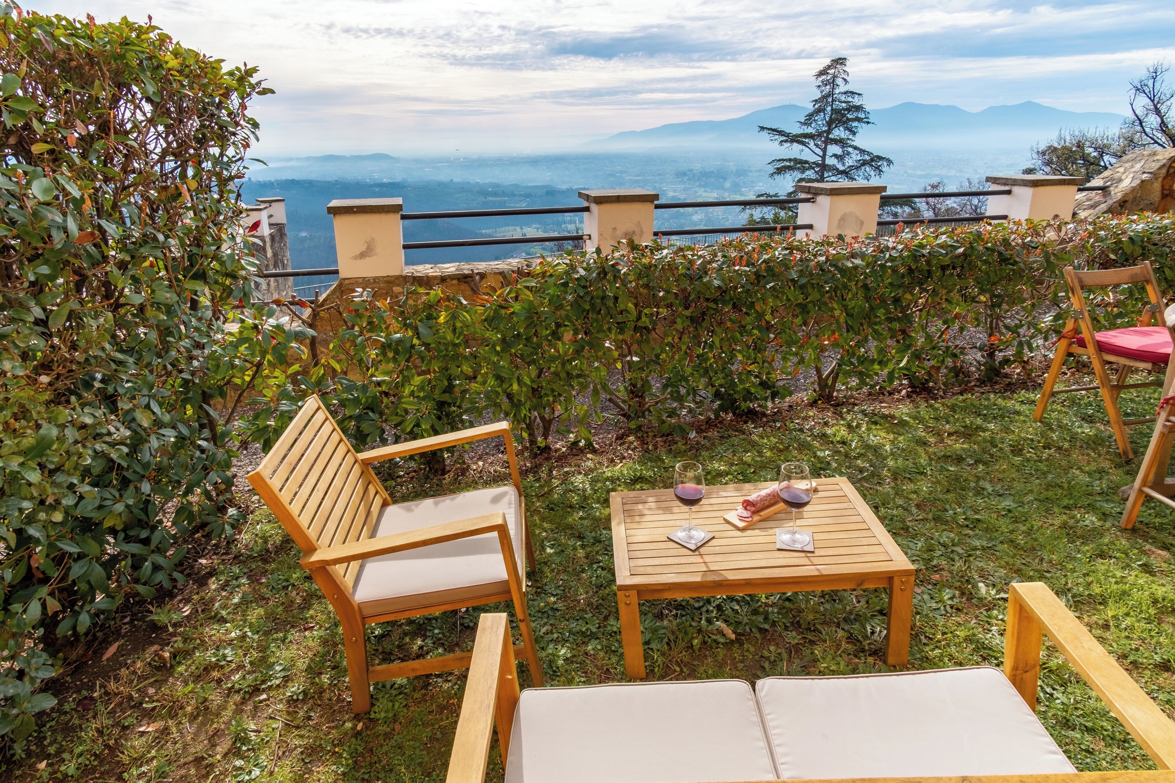 A wooden bench and table with a view of mountains and a body of water.