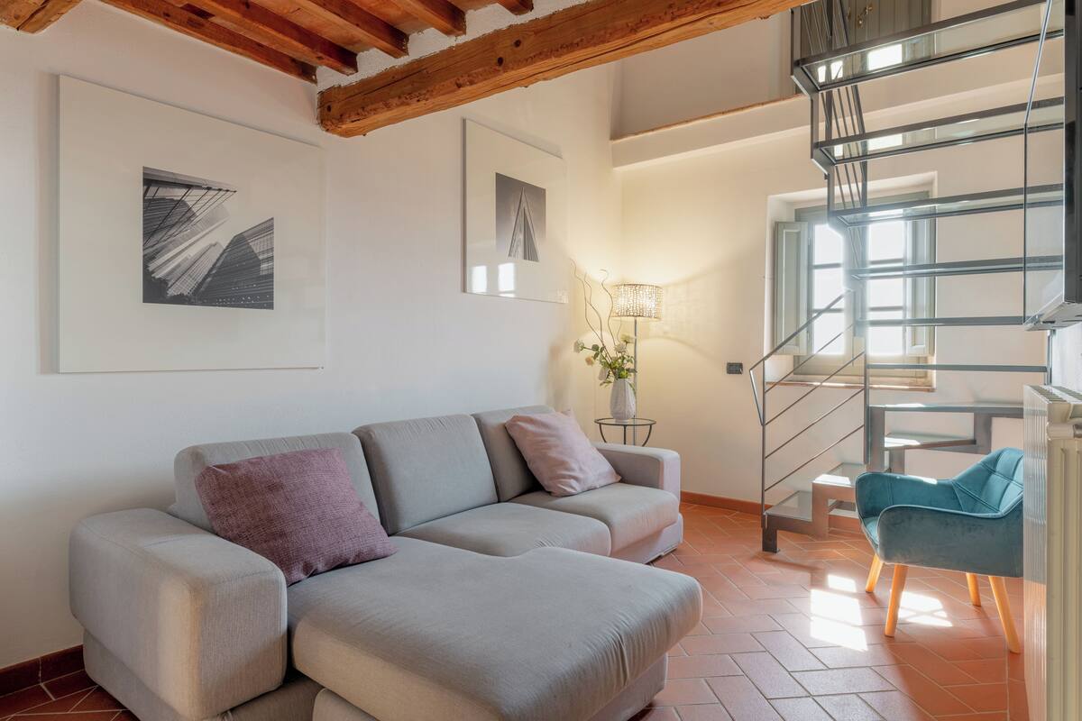 A modern living room with a sofa, a lamp, and a staircase.