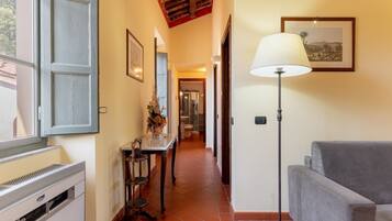 A hallway with a dining table, chairs, a standing lamp, and a sofa.