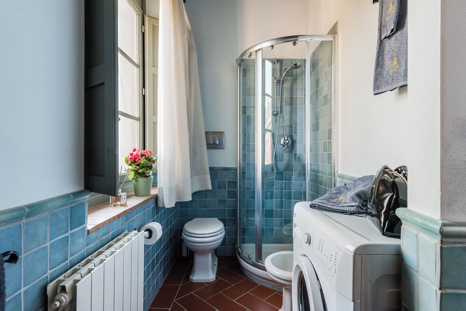Une salle de bain équipée d’une douche, de toilettes et d’un lave-linge.