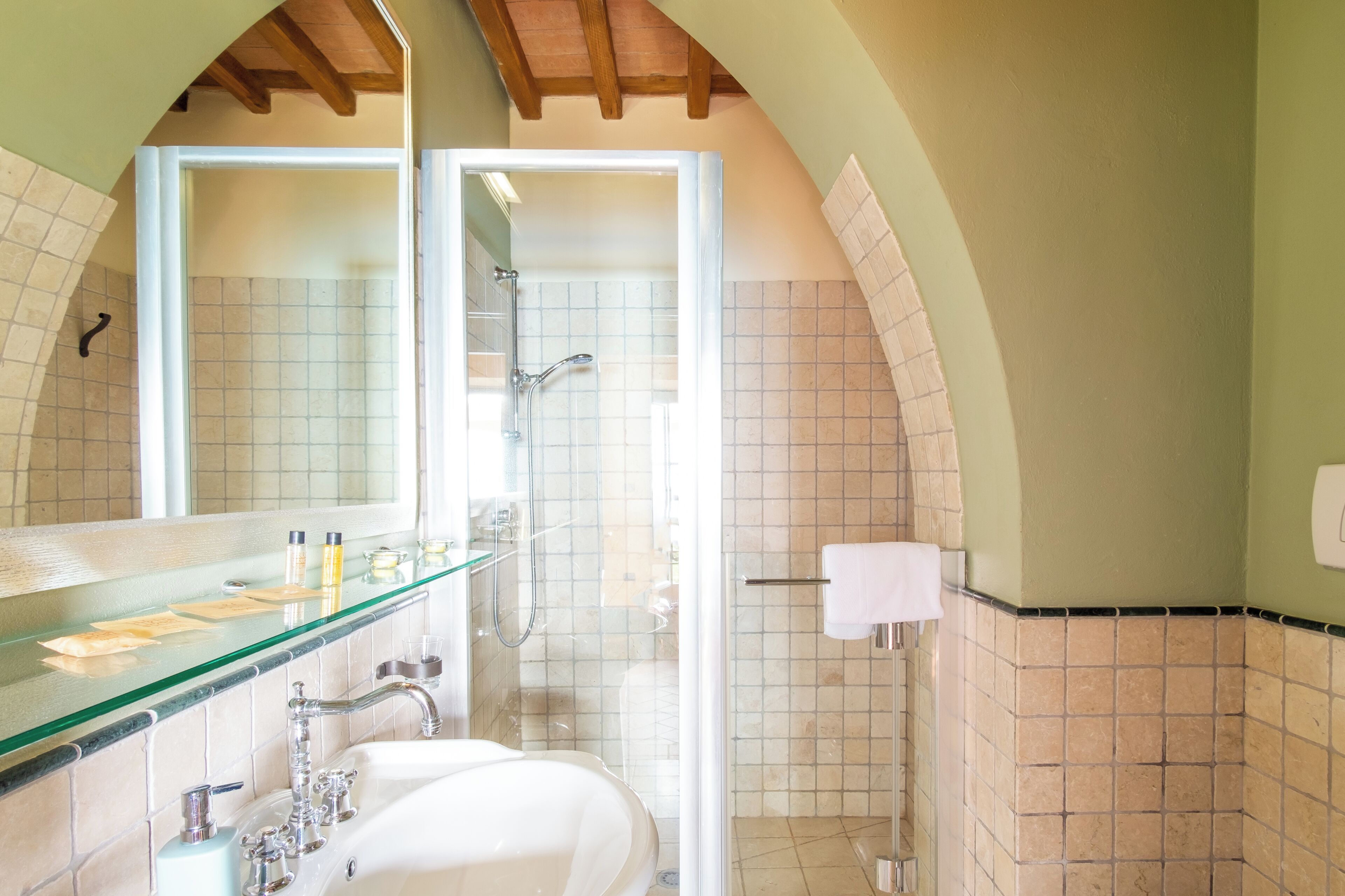 A bathroom with a glass shower enclosure, a white sink, and a large mirror.