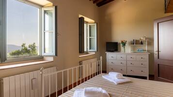 A bedroom with a bed, a dresser, a TV, and a window with a view.