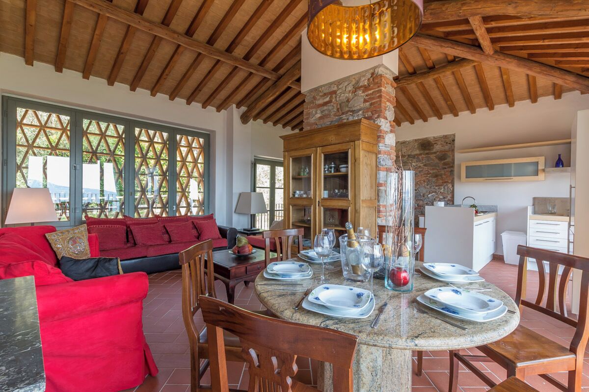 A dining area with a round table set for six, surrounded by wooden chairs.