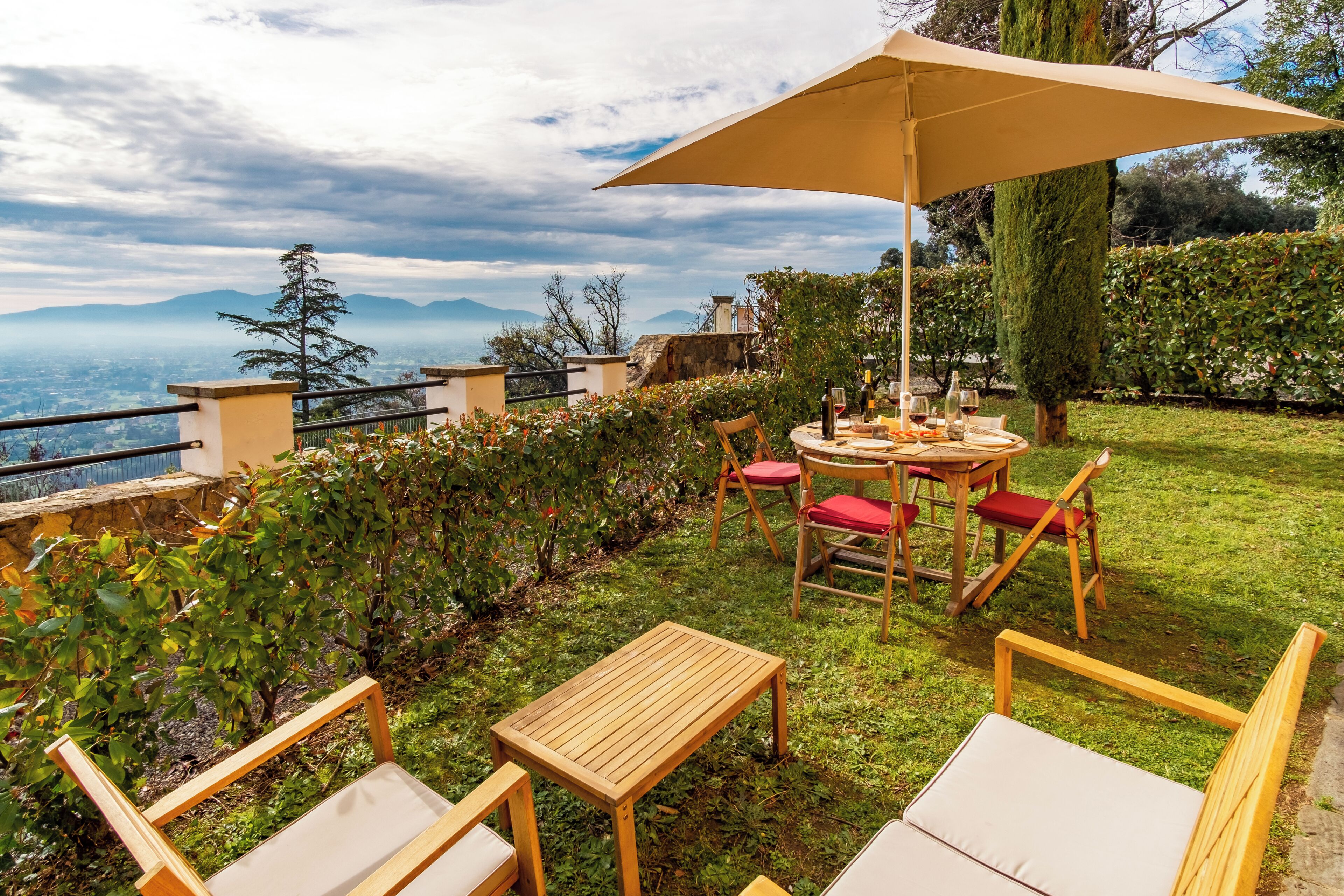 Une terrasse extérieure avec une table, des chaises et un grand parasol.