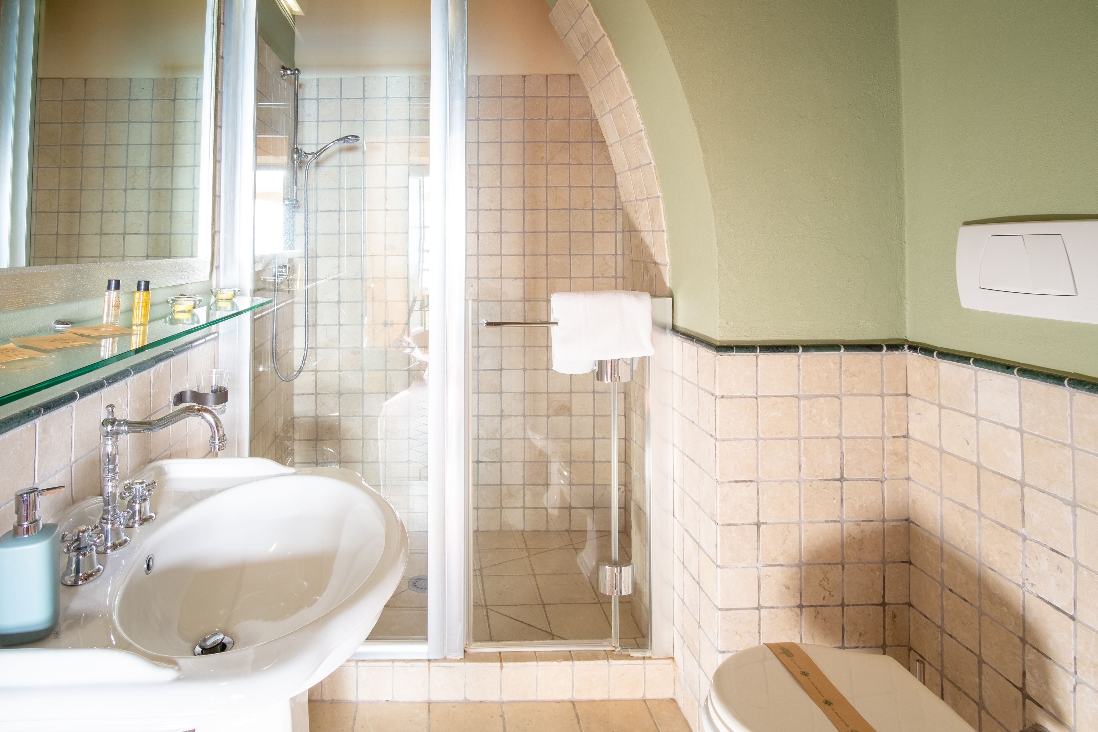 A bathroom with a glass-enclosed shower, a sink, and a toilet.