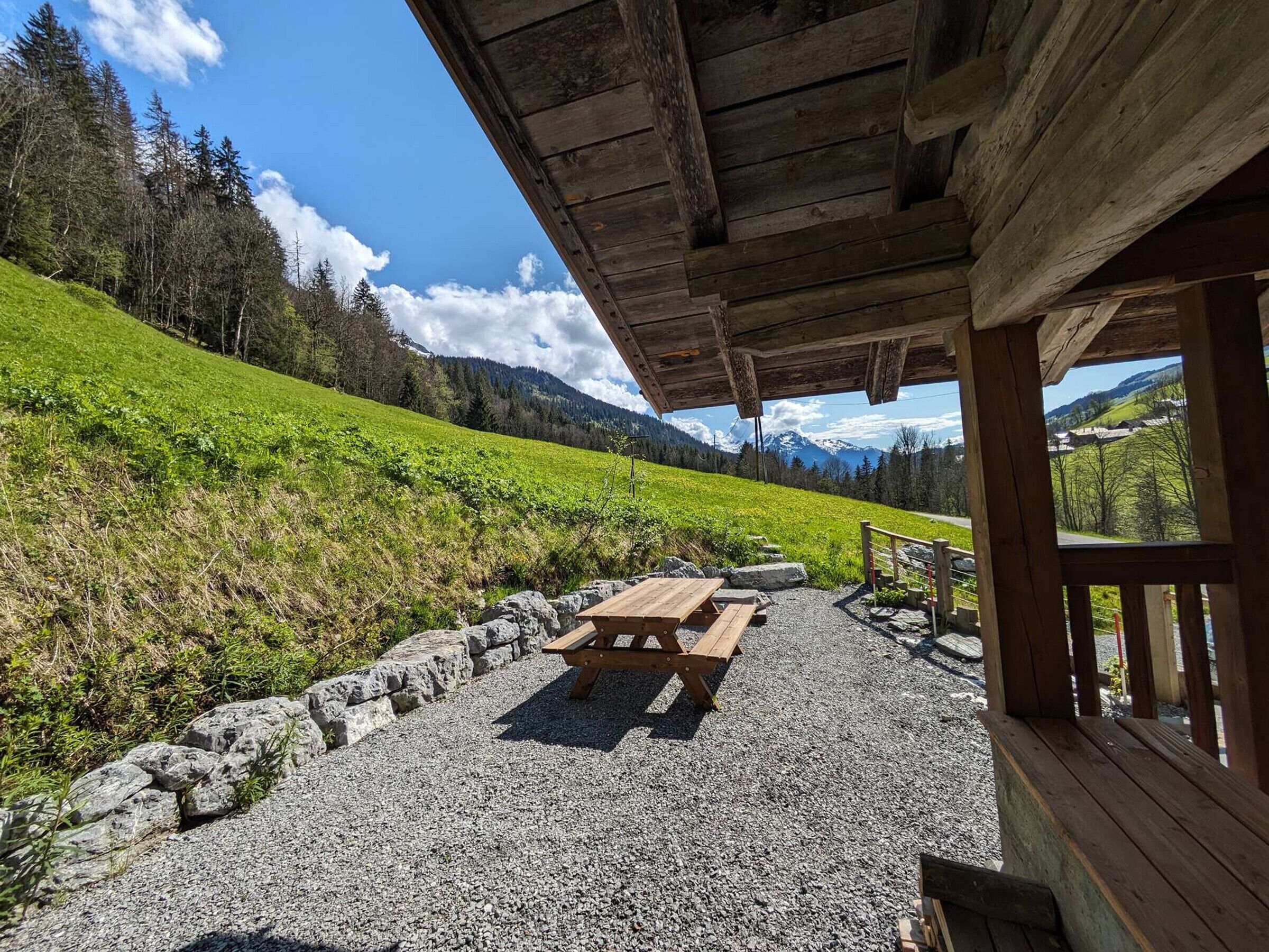 A wooden pavilion with a picnic table and stone pathway.