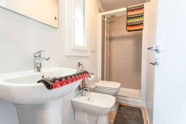 A bathroom with a white sink, a bidet, and a shower. - Centro turistico San Nicola (Peschici)