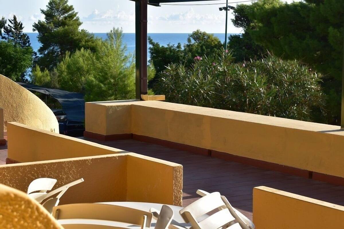 An outdoor seating area with chairs and a view of the sea.