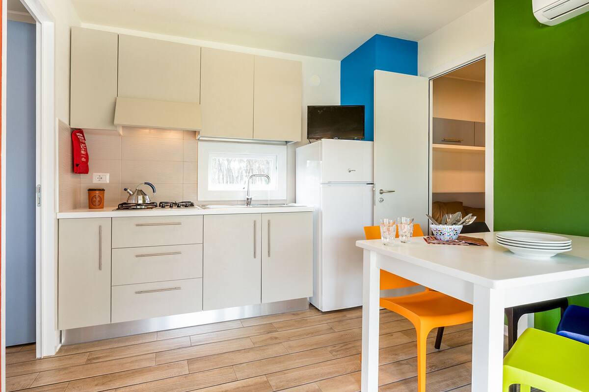 A compact kitchen with white cabinets, a white refrigerator, a gas stove, and a window.