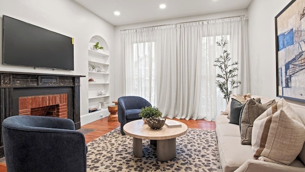 Un salon moderne avec une cheminée, un téléviseur à écran plat, une table basse ronde et un canapé.