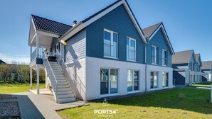 A modern two-story house with a covered porch and a staircase. - Stilvolle Ferienwohnung mit Sauna, Kamin, Terrasse und Wassernähe (Büsum)