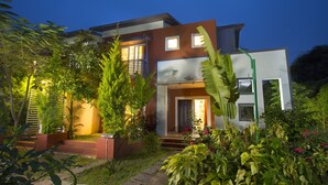 A modern two-story house with a well-maintained garden, a visible staircase, and a door leading to the entrance. - TGI Kairos (Tirupattur)