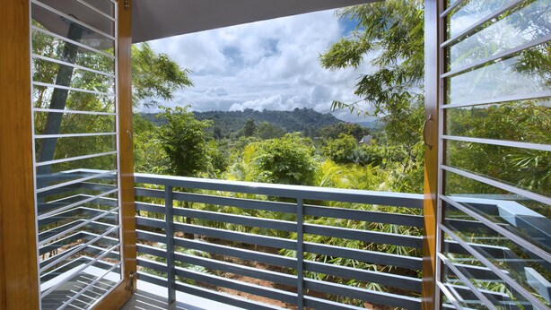 A balcony with a view of a lush landscape and distant hills. - TGI Kairos (Tirupattur)