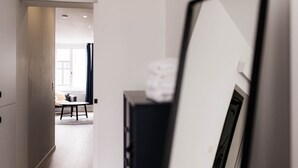 Ein Flur mit modernem Interieur, der zu einem Zimmer mit großem Fenster und einer Couch führt.