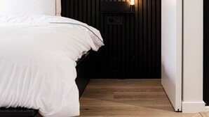 Ein Schlafzimmer mit Bett, Nachttisch mit Lampe, gerahmtem Bild an der Wand und schwarzem Kopfteil.