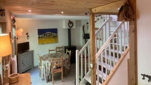 A cozy room with a wooden ceiling, a dining table with chairs, a TV, and a painting on the wall. - Spacious 3-Room Apartment for 6 with Balcony in Châtel, Near Chairlift (Châtel)