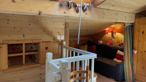 A cozy cabin interior with a wooden ceiling, a staircase, a sofa, and a small table. - Spacious 3-Room Apartment for 6 with Balcony in Châtel, Near Chairlift (Châtel)