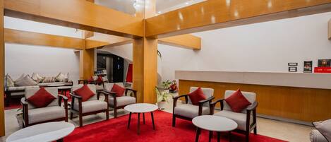 Un vestíbulo con alfombra roja, vigas de madera y un mostrador de recepción.