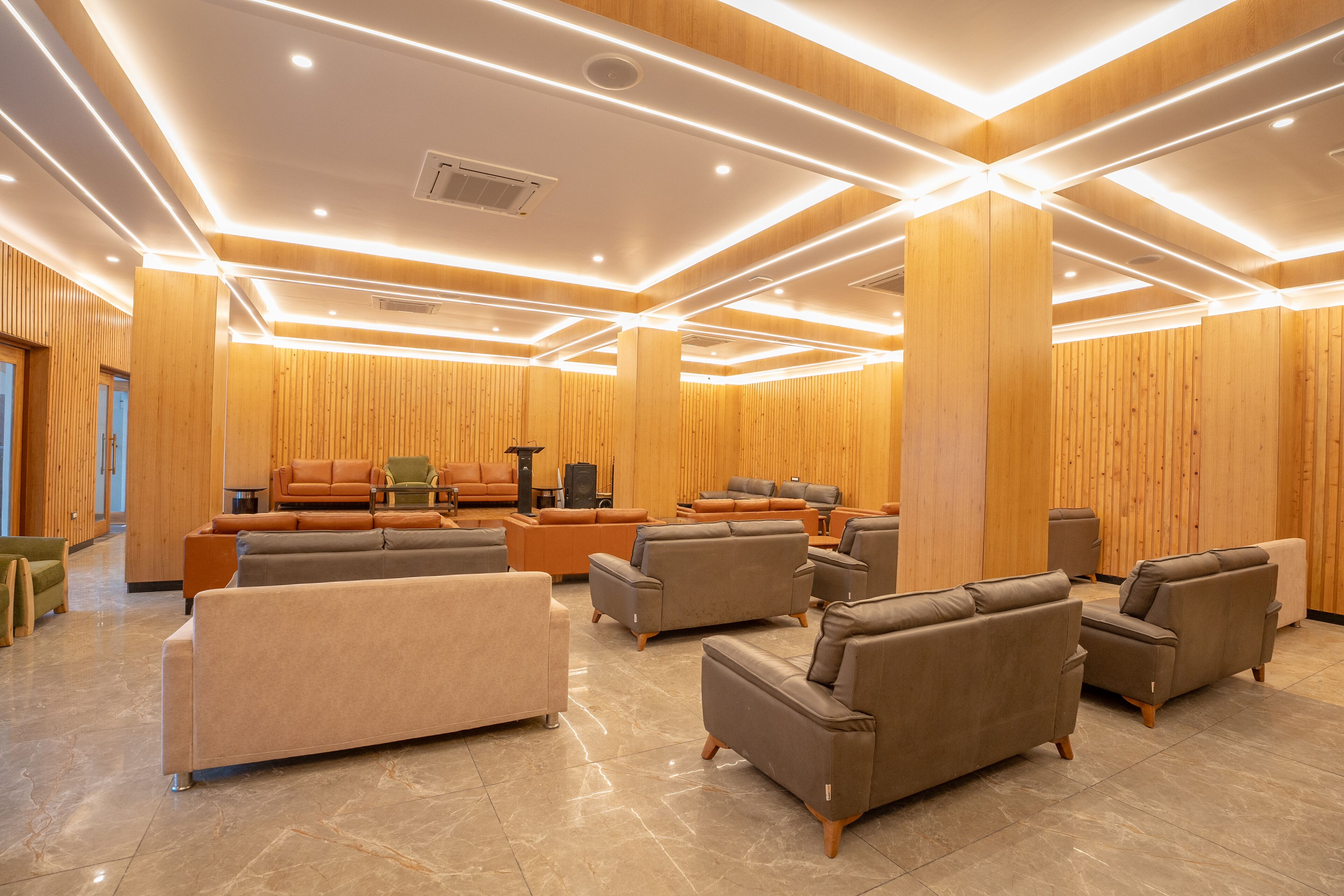 A spacious lobby with multiple seating areas, a fireplace, and a wooden wall design.