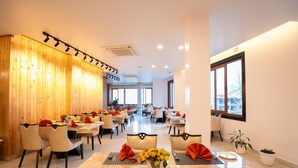 A spacious dining area with multiple tables and chairs, wooden paneling on one wall, and large windows providing natural light. - SUMMIT GRAND RESORT & SPA , GANGTOK  (Gangtok)
