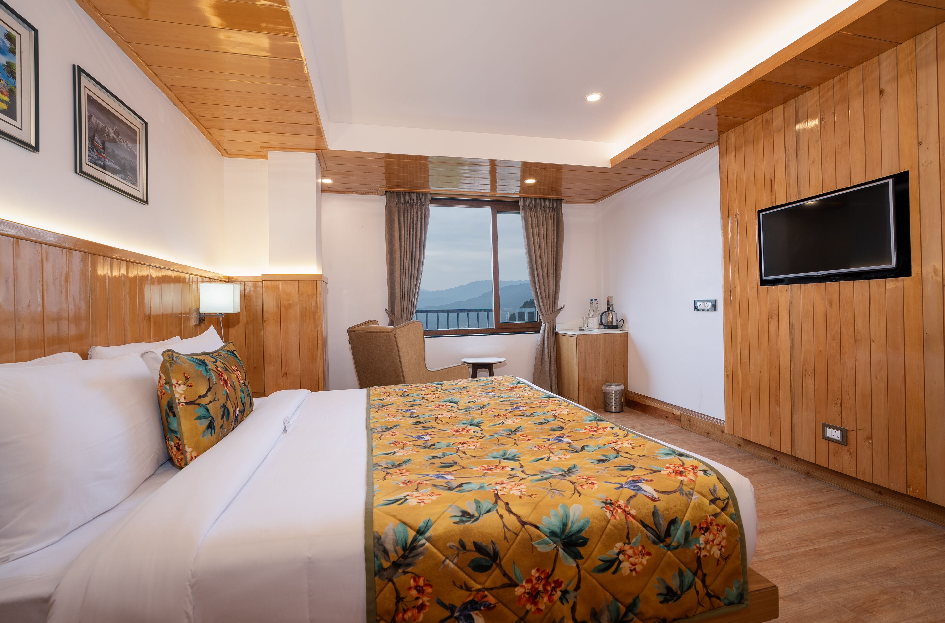 A hotel room with a bed, a desk, a chair, a TV, and a window with curtains.
