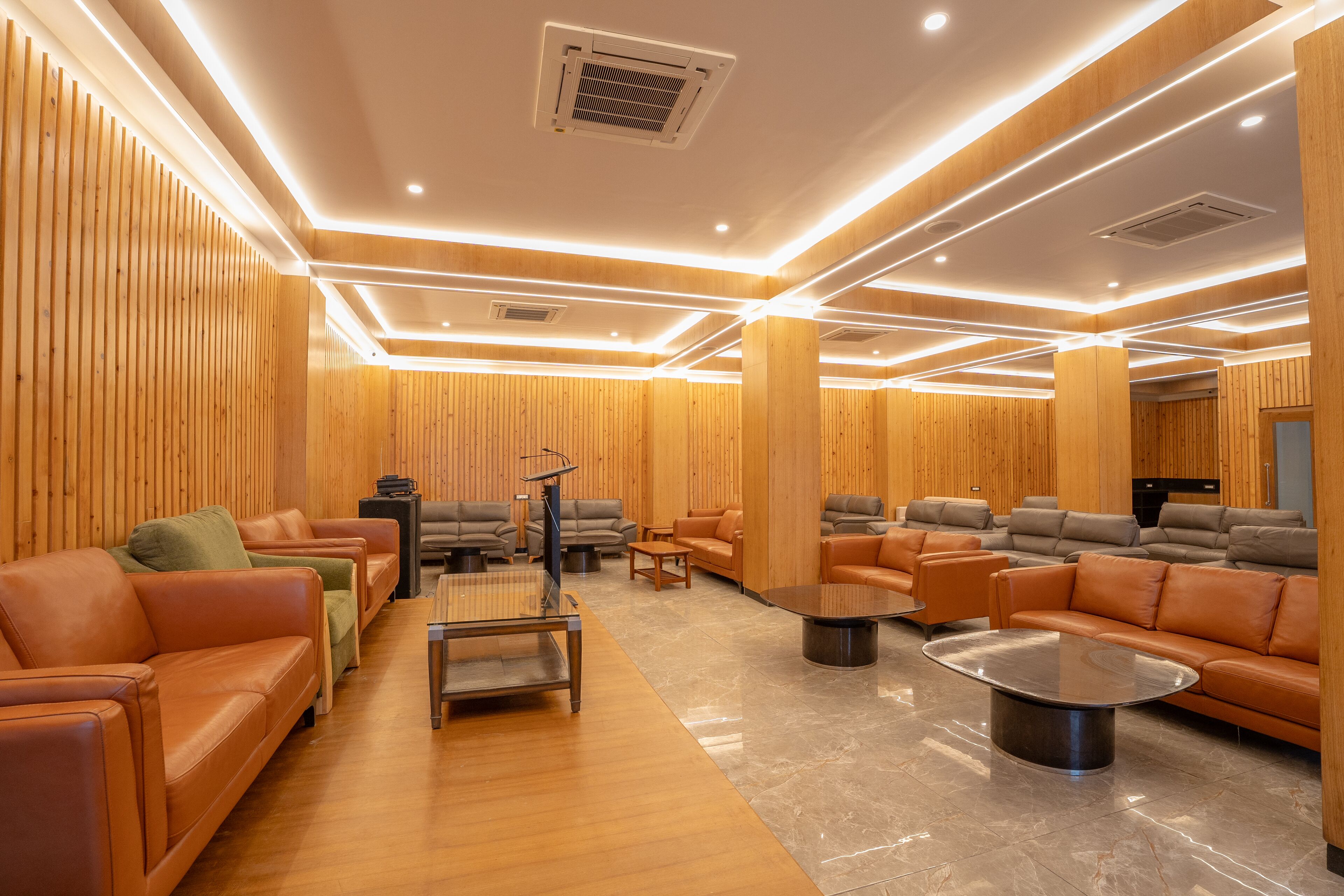 A modern lounge area with leather sofas, a coffee table, and wooden paneling.