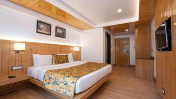Una habitación de hotel moderna con una cama de madera, mesitas de noche, un televisor y una puerta que da a un baño.