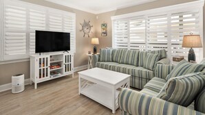 A living room with a television, sofa, coffee table, and white cabinetry. - Three Bedroom Oceanside Condo Steps from the Beach (Ocean City)