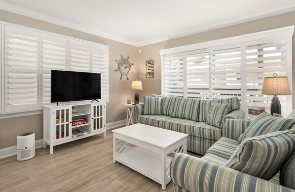 A living room with a television, sofa, coffee table, and white cabinetry.