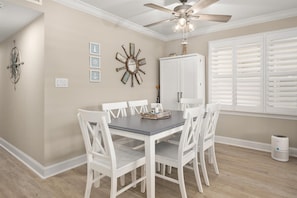 A dining room with a table, chairs, a ceiling fan, and a window with blinds.