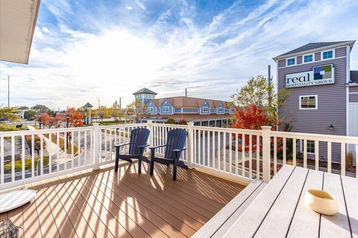 A deck with chairs and a table, a building labeled 'real hospitality group,' and a clear sky.