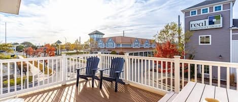 A deck with chairs and a table, a building labeled 'real hospitality group,' and a clear sky.
