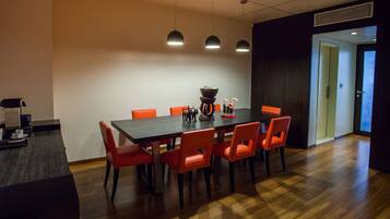 A modern dining area with a dark wooden table, red chairs, and pendant lighting.