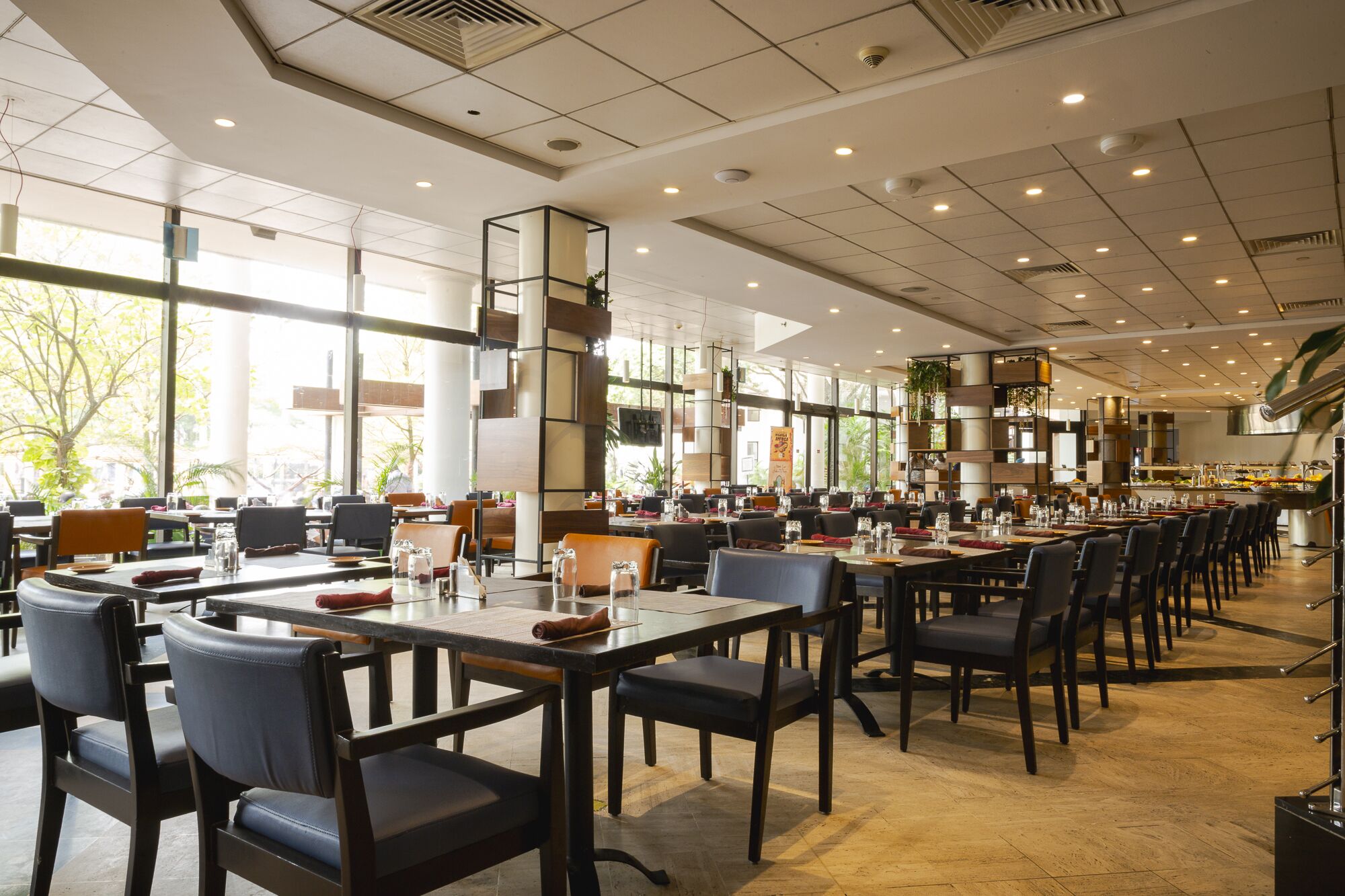 A spacious restaurant with long tables and chairs, large windows, and a modern interior design.