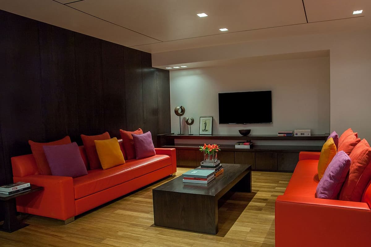 A modern living room with a red sofa, a coffee table, and a TV mounted on the wall.