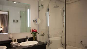 A modern bathroom with a glass-enclosed shower, a vanity with a sink, and a mirror.