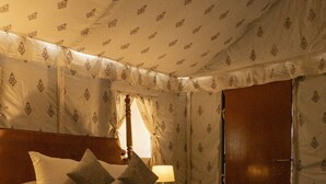 Un dormitorio con una cama de madera, cortinas estampadas y una araña.