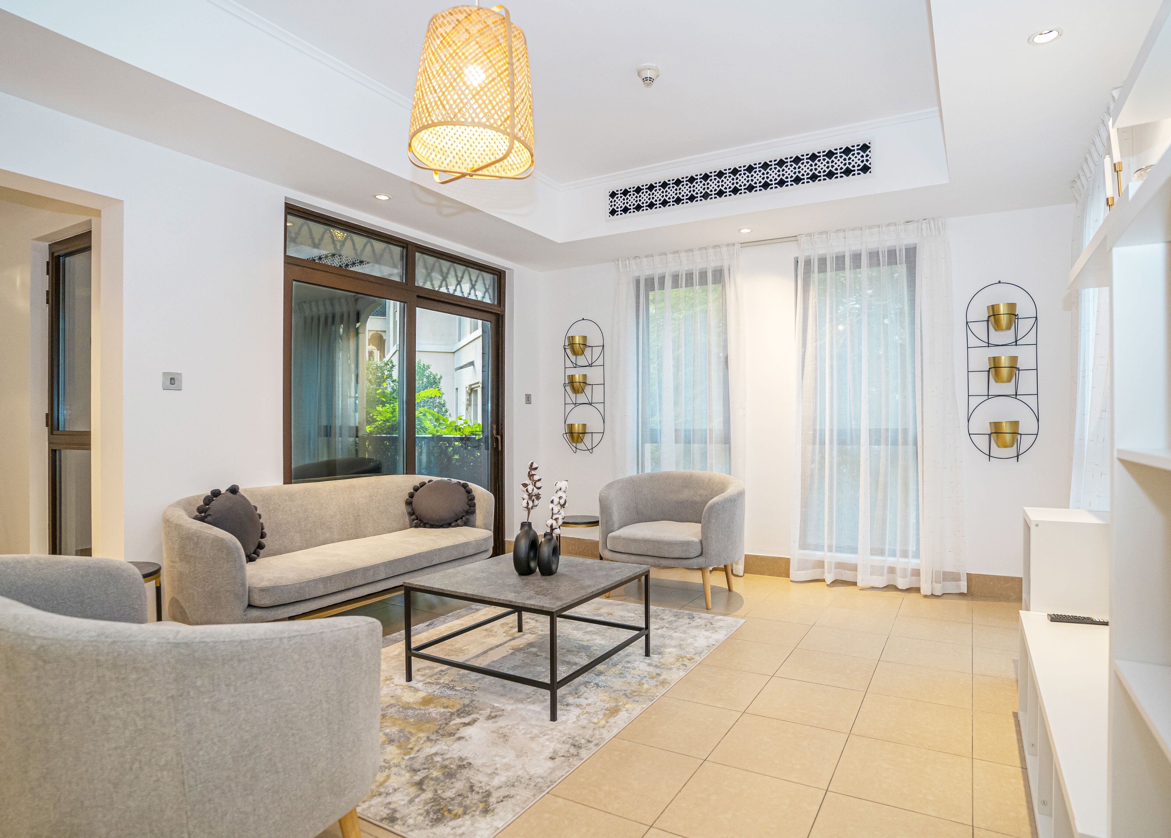 A modern living room with a sofa, armchairs, a coffee table, and decorative vases.