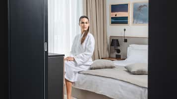 Habitación de hotel con una cama, una mesita de noche, una lámpara y dos cuadros en la pared.