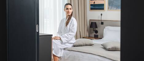 A hotel room with a bed, a nightstand, a lamp, and two framed pictures on the wall.
