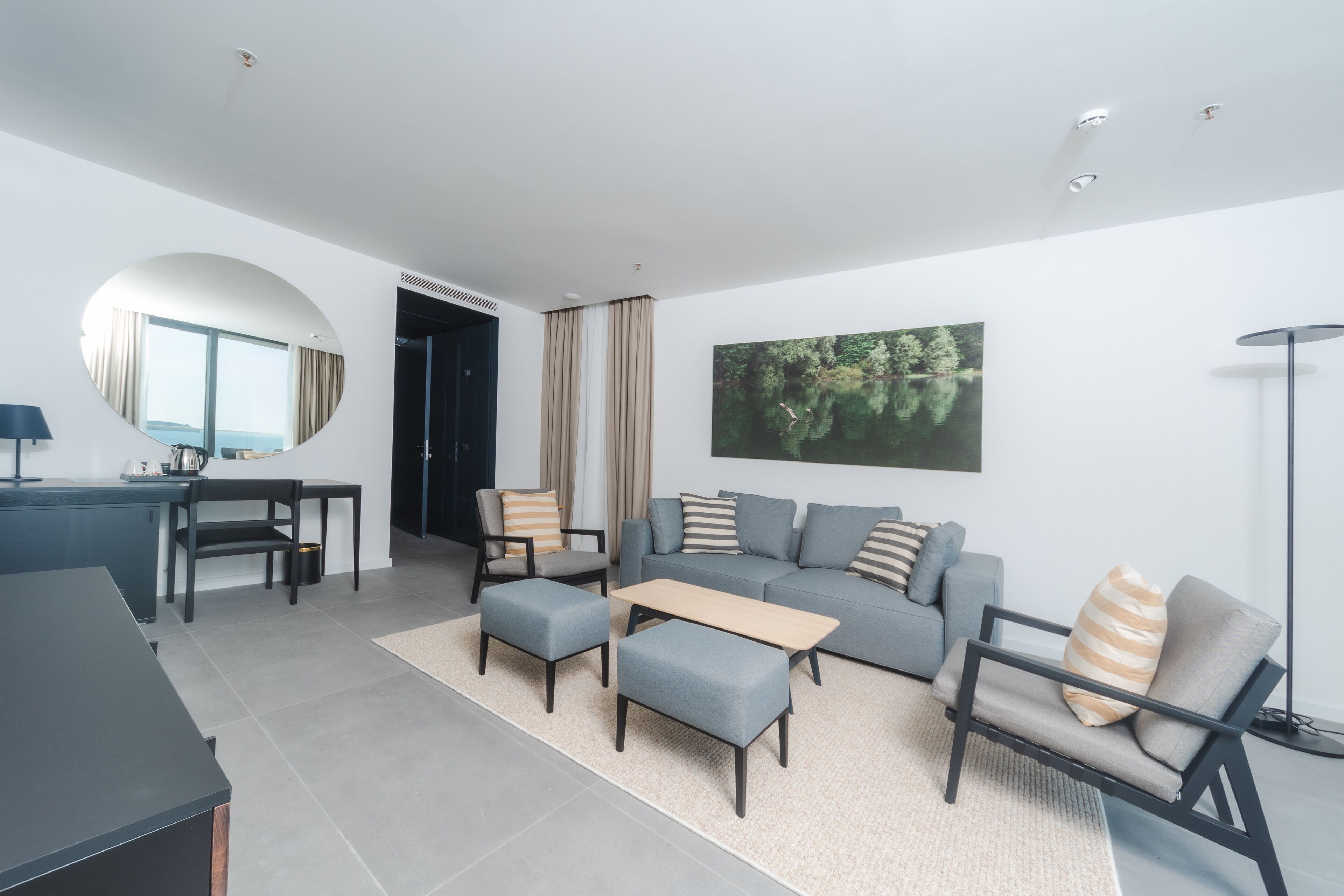 A modern living room with a grey sofa, two armchairs, a coffee table, and a dining area with a round table and chairs.